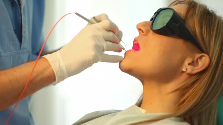 Side view of dentist and female patient being treated with laser HD 720 Side view of dentist and female patient being treated with laser HD 720