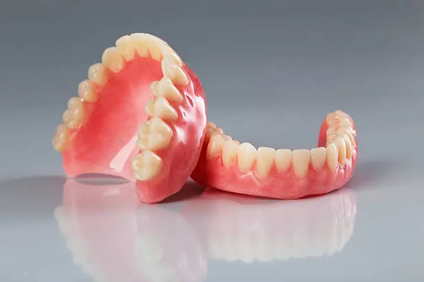 A set of dentures on a shiny gray background